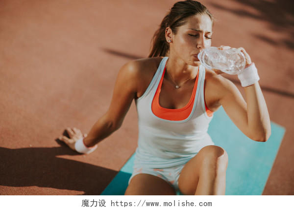 口渴的女赛跑运动员在训练后休息和喝水